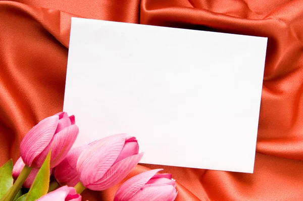 Umschlag und Blumen auf dem Satin-Hintergrund — Stockfoto