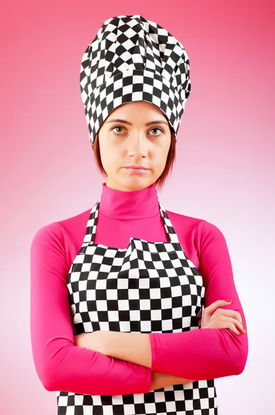 Unga kvinnliga kock mot tonad bakgrund — Stockfoto
