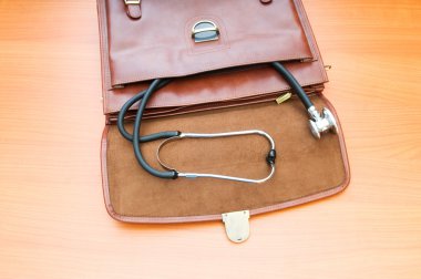 Doctor's case with stethoscope against wooden background clipart