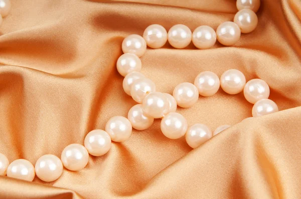 Perlenkette auf dem hellen Satinhintergrund — Stockfoto
