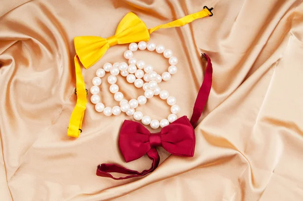 Lazos de lazo y collar de perlas en el satén —  Fotos de Stock