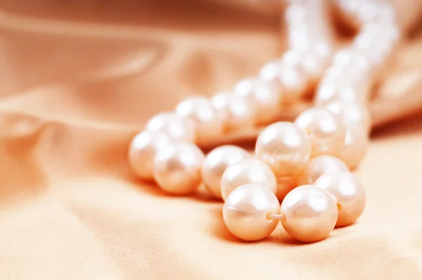 Perlenkette auf dem hellen Satinhintergrund — Stockfoto