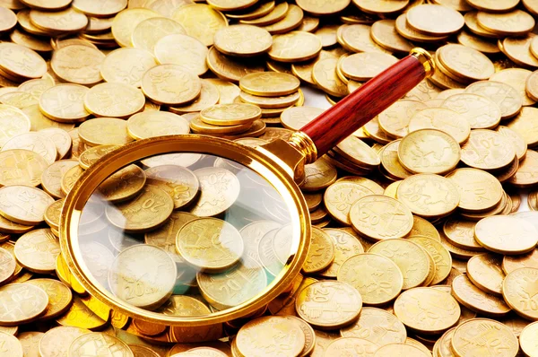 Magnifying glass and coins at the background — Stock Photo, Image
