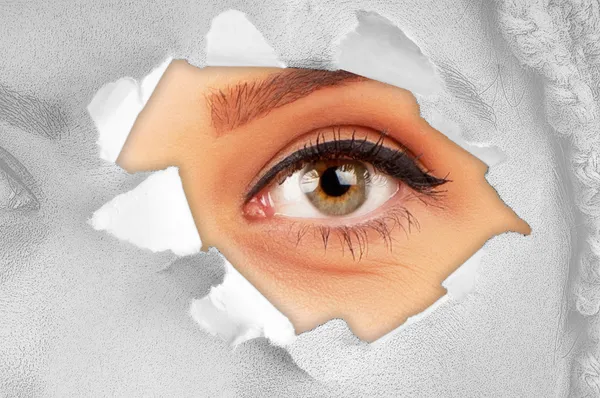Mujer ojo a través de agujero en papel — Foto de Stock