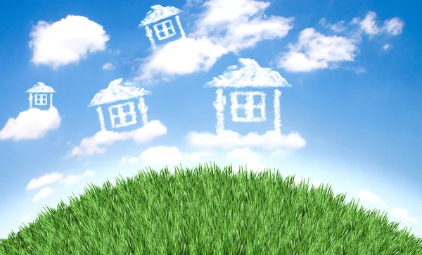Cloud houses in the air over grass field — Stock Photo, Image