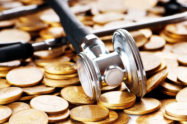 Концепция дорогостоящего здравоохранения с монетами и стетоскопом — стоковое фото