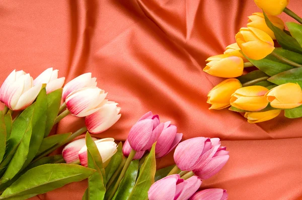 Many flowers on the red satin background — Stock Photo, Image
