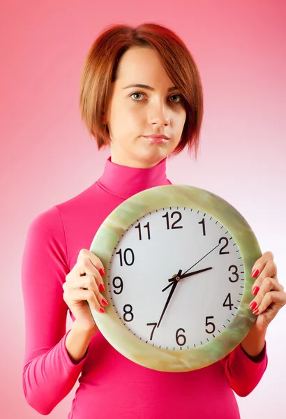 Młoda kobieta trzyma okrągły zegar w rękach — Zdjęcie stockowe