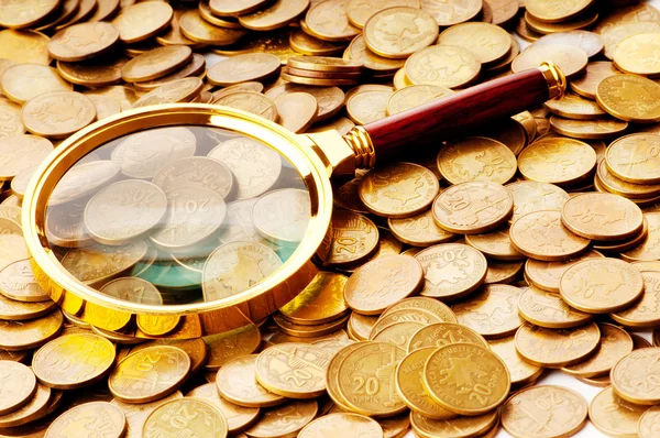 Magnifying glass and coins at the background — Stock Photo, Image
