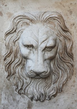 Bas-relief of a head of a lion on a wall clipart