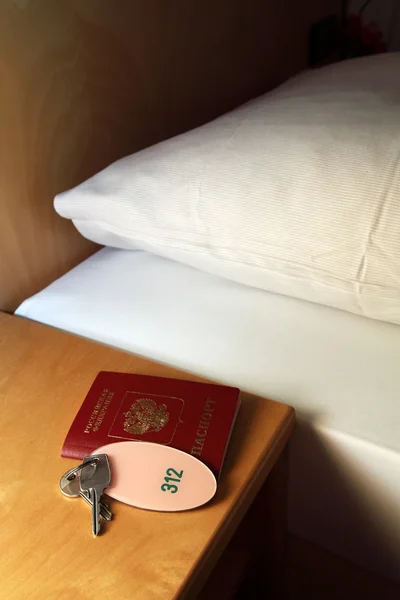 パスポートとホテルのベッドサイド テーブルの上のキー — ストック写真