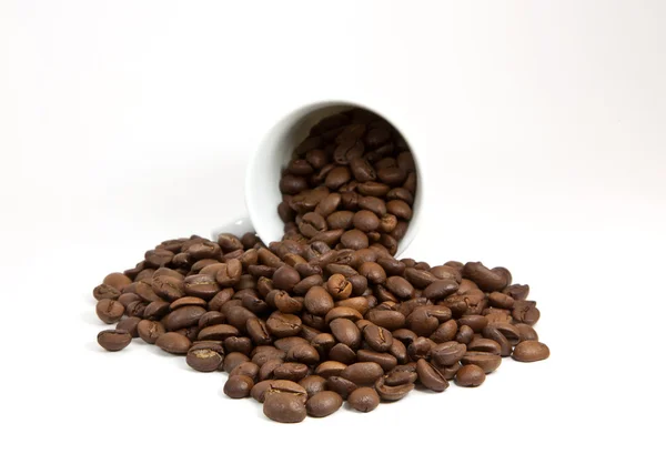 Copo virado com grãos de café no fundo branco — Fotografia de Stock