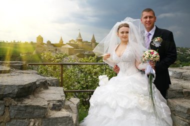 Newlyweds on the background of a beautiful old castle, a beautiful spring day clipart