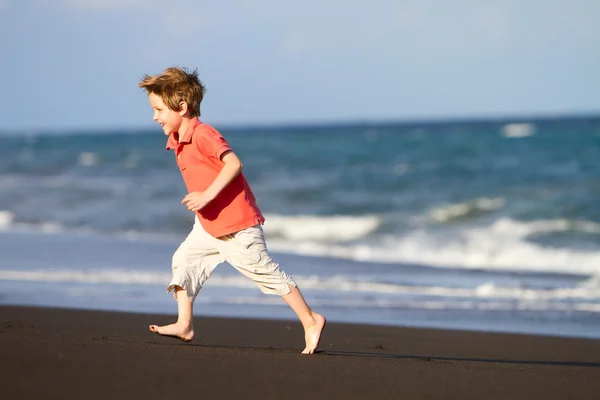Pojke på svart sandstrand — Stockfoto