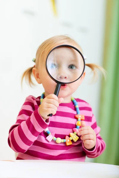 Maluch dziewczynka, patrząc przez szkło powiększające — Zdjęcie stockowe