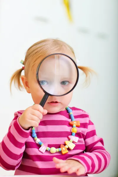 Toddler girl looking through magnifier — Stock Photo, Image