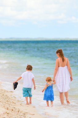 Family walking along tropical beach clipart