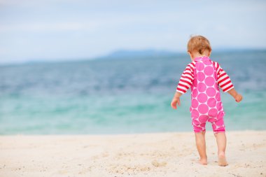 beyaz kum plajı üzerinde oturan bebek kız