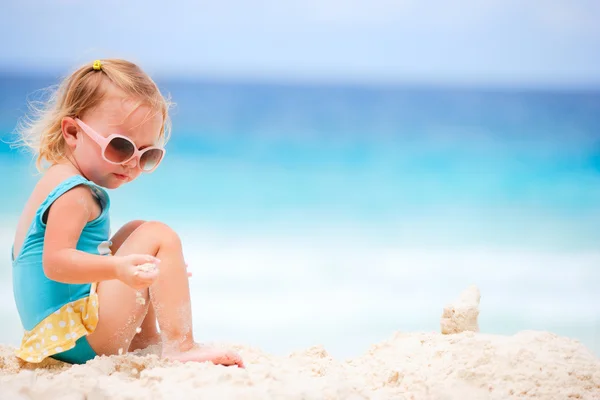 可愛いです幼児女の子遊びます上の白い砂浜 — ストック写真