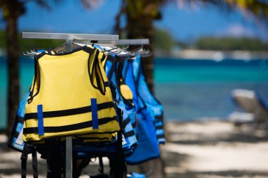 Yellow and blue life jackets on the beach clipart