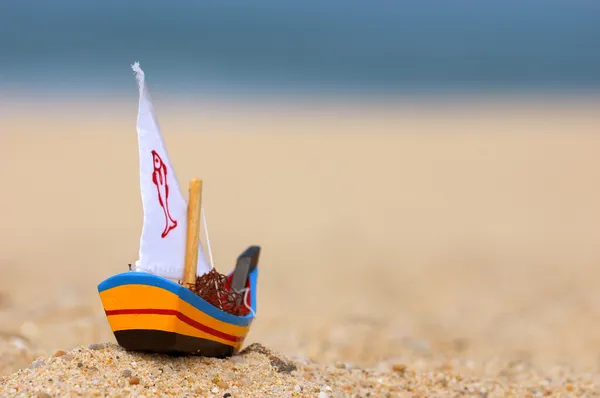 小木制渔船船玩具发送海滩上与背景的蓝色海洋 — 图库照片