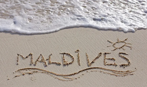 与海浪背景上的白色沙滩上写的很好马尔代夫注 — 图库照片
