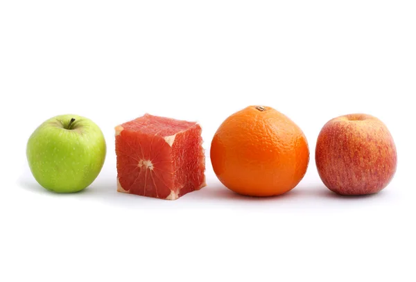 Stock image Cube shaped fresh grapefruit among round shaped fruits (green apple, red apple, orange). Conceptual image isolated on white background.