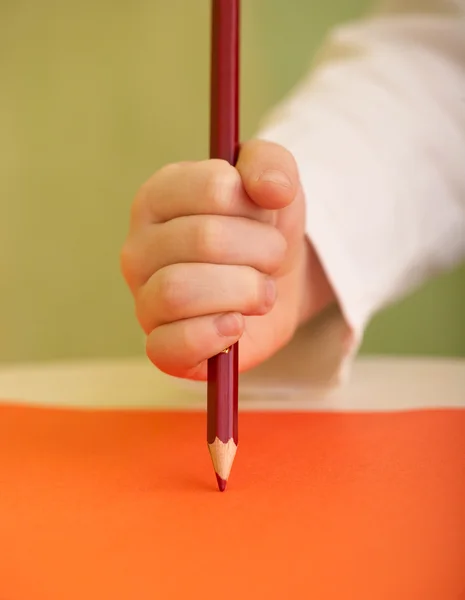 赤い鉛筆で子供の手のマクロショット — ストック写真