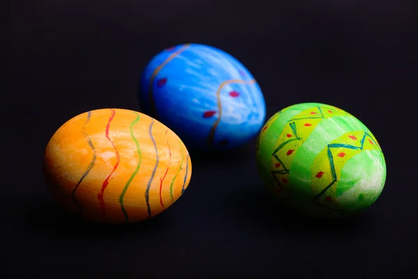 オレンジ 青と緑の復活祭の卵は黒の背景に — ストック写真