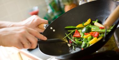 Chef cooking vegetables in wok pan clipart