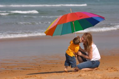 hava koşullarına bağlı değildir. mutlu genç kadın ve çocuk dışarıda eğleniyor parlak renkli şemsiyesi altında.