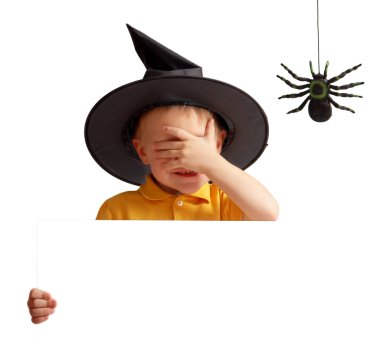 Halloween party only for adults! I am not looking :) Cute playful boy in witch hat with eyes closed by hand holds white banner. clipart