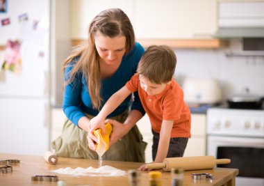 Young mother and son in kitchen making cookies.