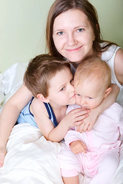 快乐年轻的母亲和她的儿子和女儿在卧室 — 图库照片