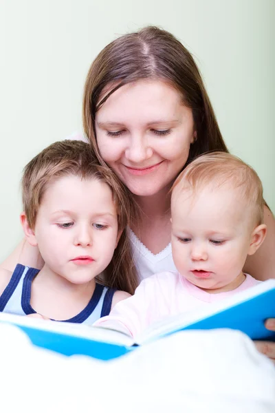Молодая Мать Двумя Детьми Читает Книгу Постели — стоковое фото