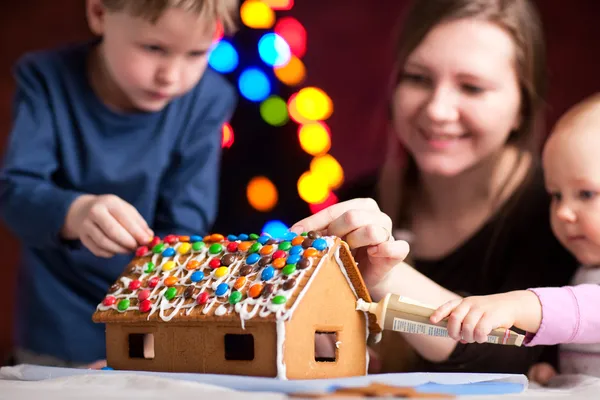 クリスマスイブに家族の飾るジンジャーブレッド家 家に焦点を当てる — ストック写真