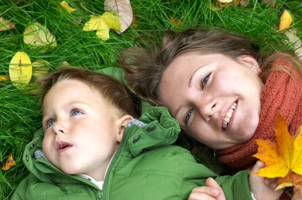 Sorrindo Mãe Filho Grama Coberto Com Folhas Caídas — Fotografia de Stock