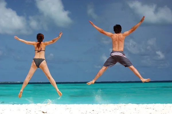 幸福开心跳跃在海滩上的情侣 — 图库照片