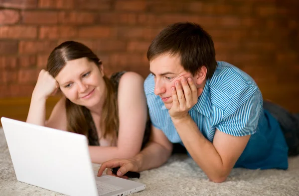 网上冲浪 在他们的家在笔记本电脑上工作的年轻夫妇 — 图库照片