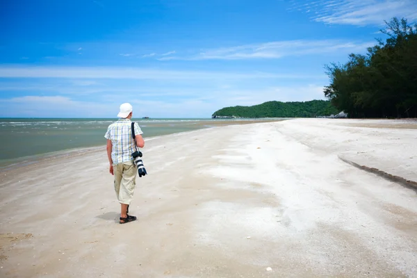 白砂热带沙滩散步的年轻摄影师 — 图库照片