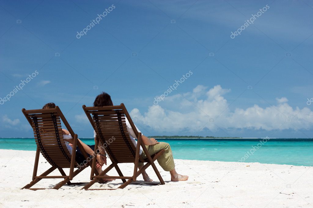 Young happy couple relaxing at tropical white sand beach