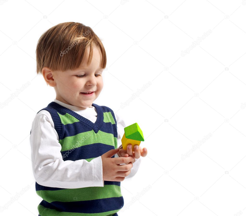 I like this house! Cute 3-years old boy with small house built from wooden blocks. Isolated on white background.