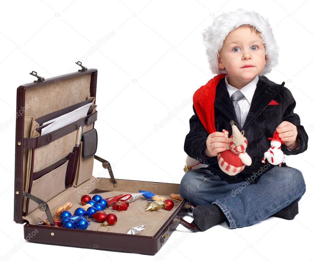 Young businessman ready for Christmas. Studio shot of very cute young businessman in Santa hat packing Christmas tree toy inside business case.