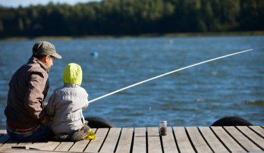 Father and small son fishing together on lake clipart