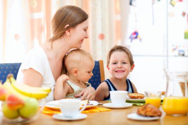 Genç mutlu anne ve iki çocukla birlikte kahvaltı ediyor
