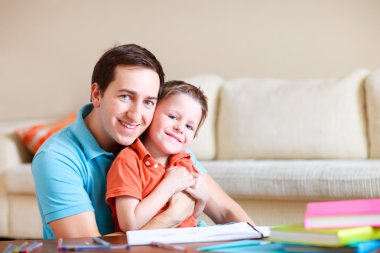 Young father and his son drawing and reading together clipart