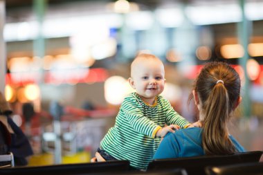 Mother and baby daughter waiting their flight at airport clipart