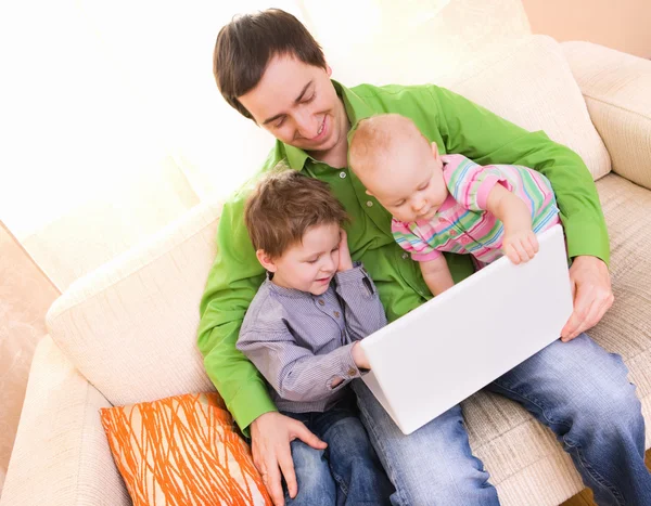 年轻的父亲和两个孩子用的笔记本电脑 — 图库照片
