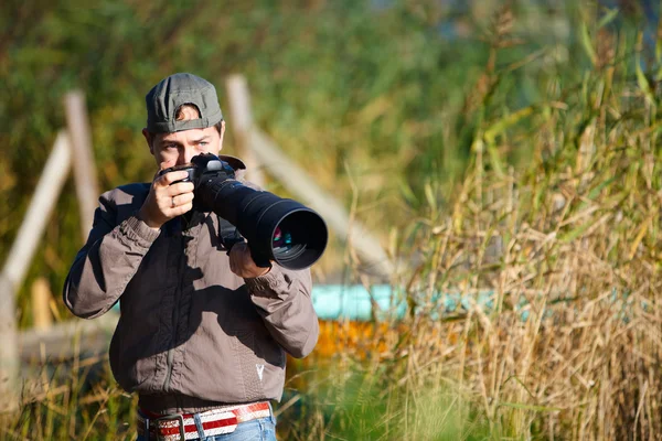 stock image Young nature photographer taking photos using telephoto lens