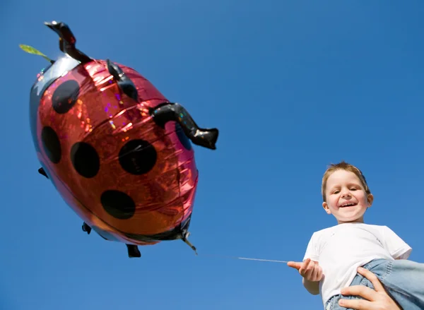 可爱的小男孩和瓢虫气球在蓝蓝的天空背景 — 图库照片